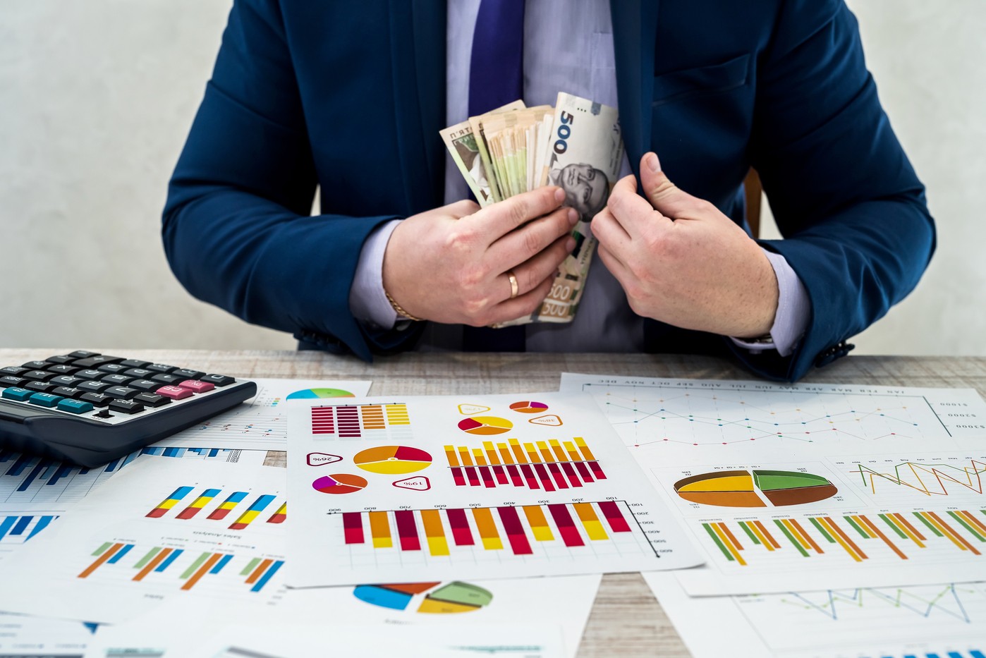 young businessman in office counts money as profit after a successful deal. The man compares and points to profit.